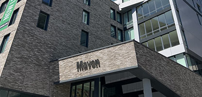 Looking up at The Maven's brick facade. A building and the sky are in the background.